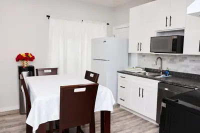 a kitchen with white cabinets and a table with chairs at Anukc in Prince George