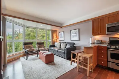 a living room with a couch and a kitchen at Le Chamois 307 by Outpost Whistler in Whistler