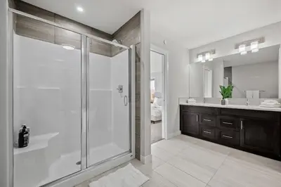 a white bathroom with a shower and a sink at The Herron Rise Retreat in Calgary
