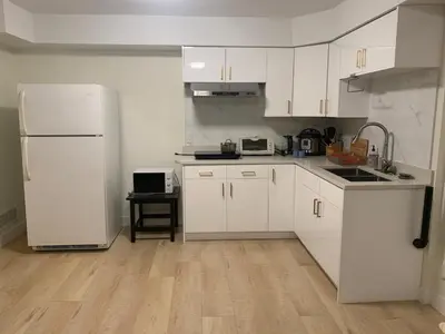 a kitchen with white cabinets and a white refrigerator at Modern 2-Bedroom suite in Burnaby