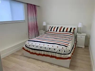 a bedroom with a bed with a striped blanket on it at Modern 2-Bedroom suite in Burnaby