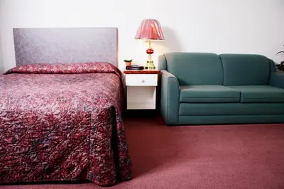 a bedroom with a bed and a couch and a chair at Country Club Inn in Lacombe