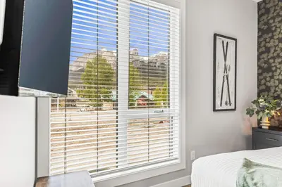 a bedroom with a large window with blinds at Luxury 4BR with Hot Tub Mtn Views 10Min Walk to DT in Canmore