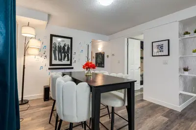 a dining room with a table and white chairs at Urban Retreat Suits 2 Bedroom & Feature Packed in Calgary