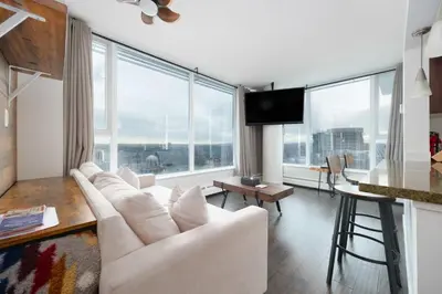 a living room with white furniture and large windows at Sub-Penthouse Condo with Jacuzzi Pool Sauna & Gym in Vancouver