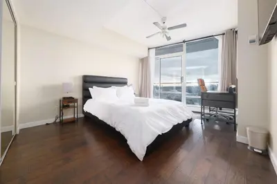 a white bedroom with a bed and a window at Sub-Penthouse Condo with Jacuzzi Pool Sauna & Gym in Vancouver