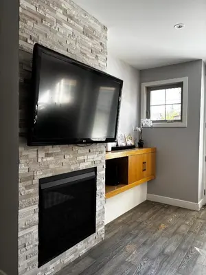 a flat screen tv hanging on a brick fireplace at Nature Home Near Downtown and 17th Avenue in Calgary