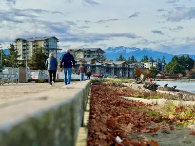 a group of people walking down a sidewalk near the water at Island Coastal Retreat in Qualicum Beach