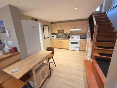 a kitchen with a staircase and a kitchen with a table at NEW Midtown Rossland Studio Apartment in Rossland