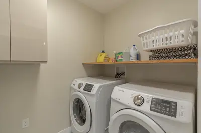 a laundry room with a washing machine and a shelf at Comfort Tenacity in Yellowknife
