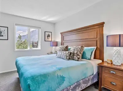 a bedroom with a large bed with a wooden headboard at Rockies 3BR Townhome w Stunning Views Near DT in Canmore