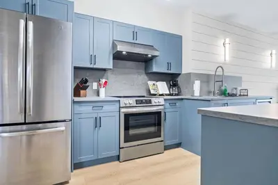 a kitchen with blue cabinets and a stainless steel refrigerator at Newly Renovated 3BR Condo with Hot Tub and MTN Views in Canmore