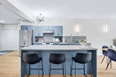 a kitchen with a large blue island with chairs at Newly Renovated 3BR Condo with Hot Tub and MTN Views in Canmore
