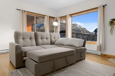 a living room with a couch and a large window at Spacious 3 BR Condo with Gym and Hot tub in Canmore