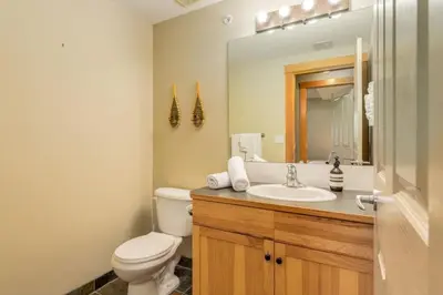 a bathroom with a toilet and a sink and a mirror at Spectacular 3BR Mountain Views with Hot Tub and Gym in Canmore