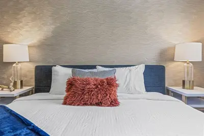 a bed with a red pillow on it with two lamps at Free Arcade Delightful Stay in Rocky Mountains in Dead Man's Flats