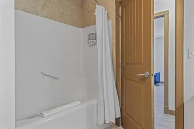 a bathroom with a shower with a white shower curtain at Free Arcade Delightful Stay in Rocky Mountains in Dead Man's Flats
