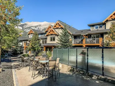 a patio with a table and chairs in front of a house at Free Arcade Delightful Stay in Rocky Mountains in Dead Man's Flats