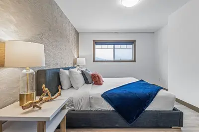 a bedroom with a bed with a blue blanket on it at Free Arcade Delightful Stay in Rocky Mountains in Dead Man's Flats