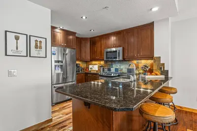 a kitchen with wooden cabinets and a granite counter top at 2BR Modern Luxe Condo with Hot Tub and Views in Canmore