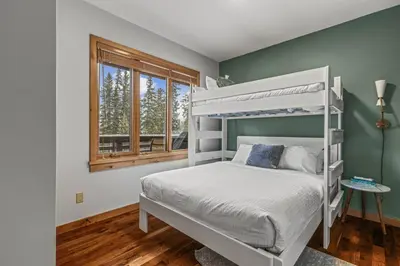 a bedroom with a white bunk bed and a window at 2BR Modern Luxe Condo with Hot Tub and Views in Canmore