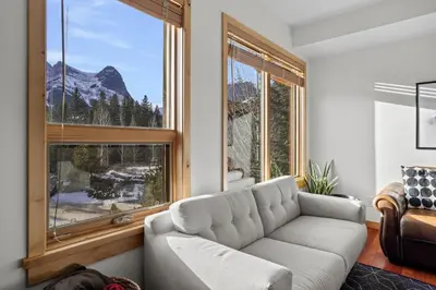 a living room with a couch and a large window at Mountain Views Lux 2BR Condo in Canmore with Hot Tub in Canmore