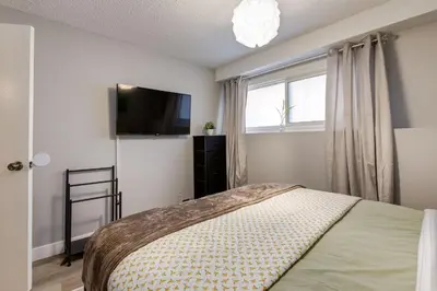 a bedroom with a bed and a flat screen tv at Casablanca - 3 BR Family & Game Haven in Calgary