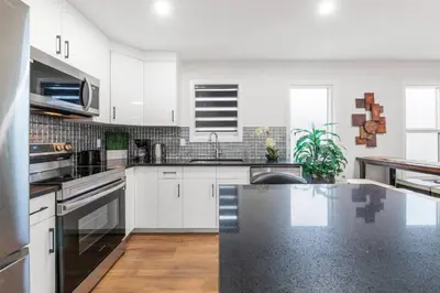 a kitchen with white cabinets and a black counter top at Spacious Home • 3BR • Close to Whyte and Downtown in Edmonton