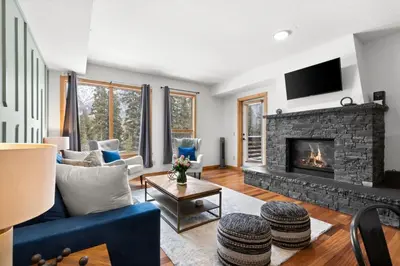 a living room with a blue couch and a fireplace at Luxurious Condo Mountain Views Hot-tub and Billiards in Canmore