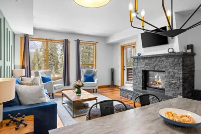 a living room with a blue couch and a fireplace at Luxurious Condo Mountain Views Hot-tub and Billiards in Canmore