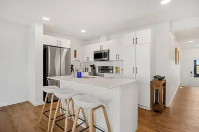 a kitchen with white cabinets and a bar with stools at Luxury Family Retreat with Games, King Bed and Garage in Edmonton
