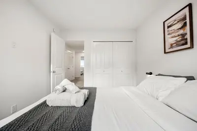 a white bedroom with a bed and towels on the floor at Single Detached Full House with Ping Pong King Bed and Garage in Edmonton