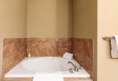 a bath tub in a bathroom with brown tiles at El Paraiso - Luxury Downtown Penthouse in Canmore
