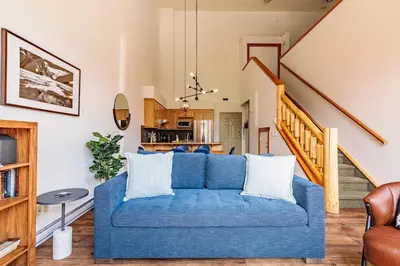 a living room with a blue couch and a staircase at Cloud Nine - Stunning Views Rooftop Hot Tub in Canmore
