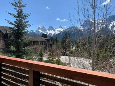 a view of snow covered mountains from a wooden fence at Spring Creek Serenity at Rundle Cliffs Lodge in Canmore