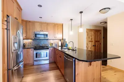 a kitchen with stainless steel appliances and wooden cabinets at Spring Creek Serenity at Rundle Cliffs Lodge in Canmore