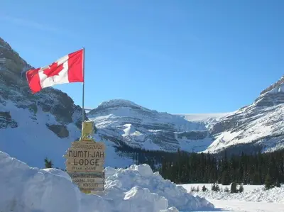 a canadian flag on top of a snow covered mountain at Spring Creek Serenity at Rundle Cliffs Lodge in Canmore