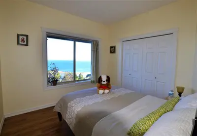 a dog sitting on a bed in a bedroom with a window at Gibralter Rock Ocean View B&B in Nanaimo