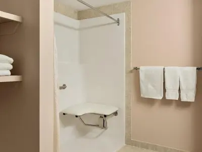 a bathroom with a shower with a bench and towels at Canada Grey Motor Inn in Hanna
