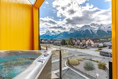 a hot tub on a balcony with a view of mountains at Ravens Peak - Private Hot Tub in Canmore