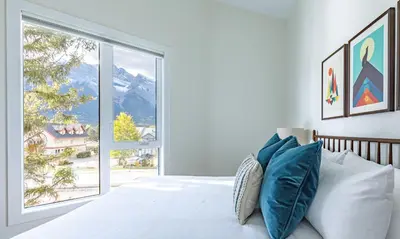 a bedroom with a bed and a large window at Ravens Peak - Private Hot Tub in Canmore