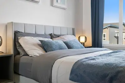 a large bed with blue pillows in a bedroom at Luxe Retreat with Gym, Ping Pong, King Bed, Near WEM in Edmonton