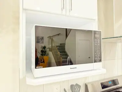 a microwave hanging on a wall in a kitchen at Spacious 4 Beds Sleeps 8 Near Airport Family Home in Nisku