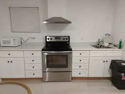 a kitchen with a stainless steel stove and white cabinets at 43 Erin Woods Drive SE Calgary in Calgary