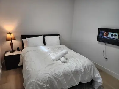 a bedroom with a white bed with a tv on the wall at Cozy, Classy 2 BedRM Private Suite with Netflix and Parking in Edmonton