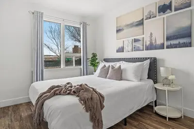 a white bedroom with a large bed and a window at Blue Raptor Family-Friendly 3BR Private Yard in Drumheller