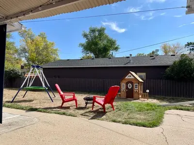 a playground with two red chairs and a swing at Blue Raptor Family-Friendly 3BR Private Yard in Drumheller