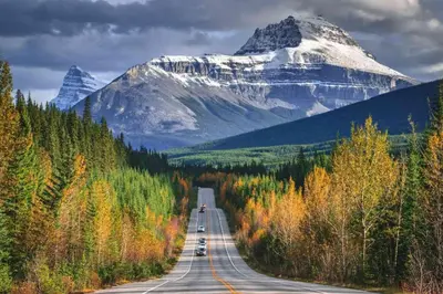 a highway with a snow covered mountain in the background at Mountaineer Creekside Cabin - Private Hot Tub in Golden