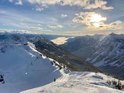 a view of a snowy mountain with the sun in the background at Explorer Creekside Cabin - Private Hot Tub in Golden