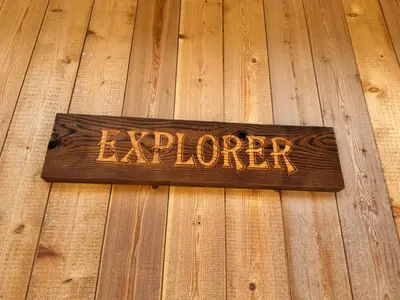 a sign that says explorer sitting on a wooden floor at Explorer Creekside Cabin - Private Hot Tub in Golden